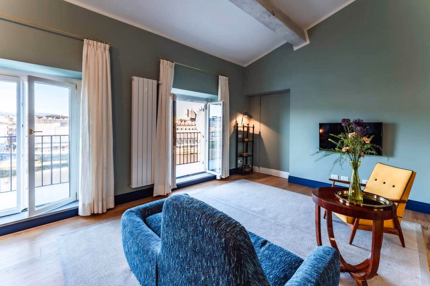 Luxury View Arno — sage-green living room with French doors to the balcony