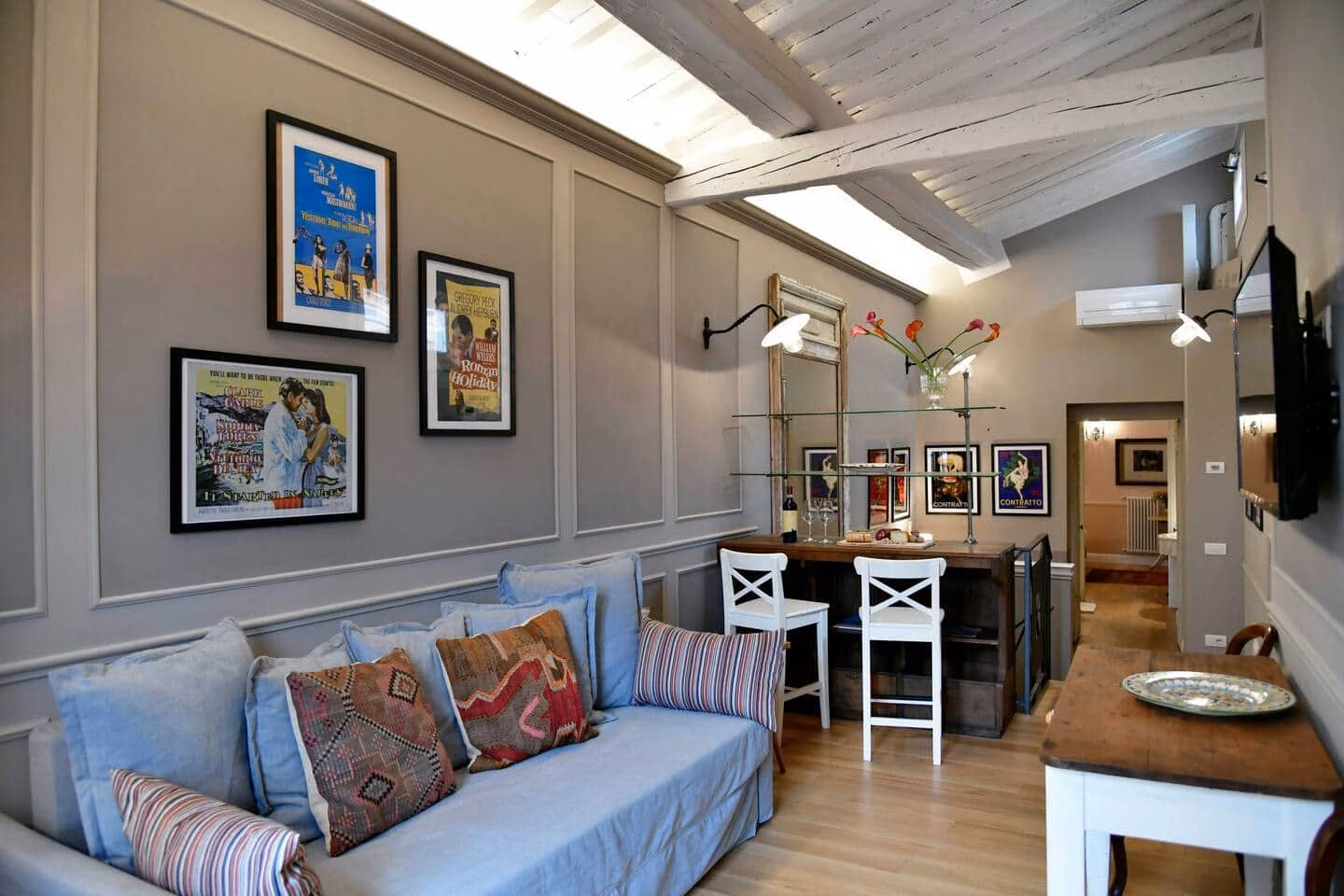Il Bue Terrace Apartment — living room with a blue sofa and framed vintage Italian film posters