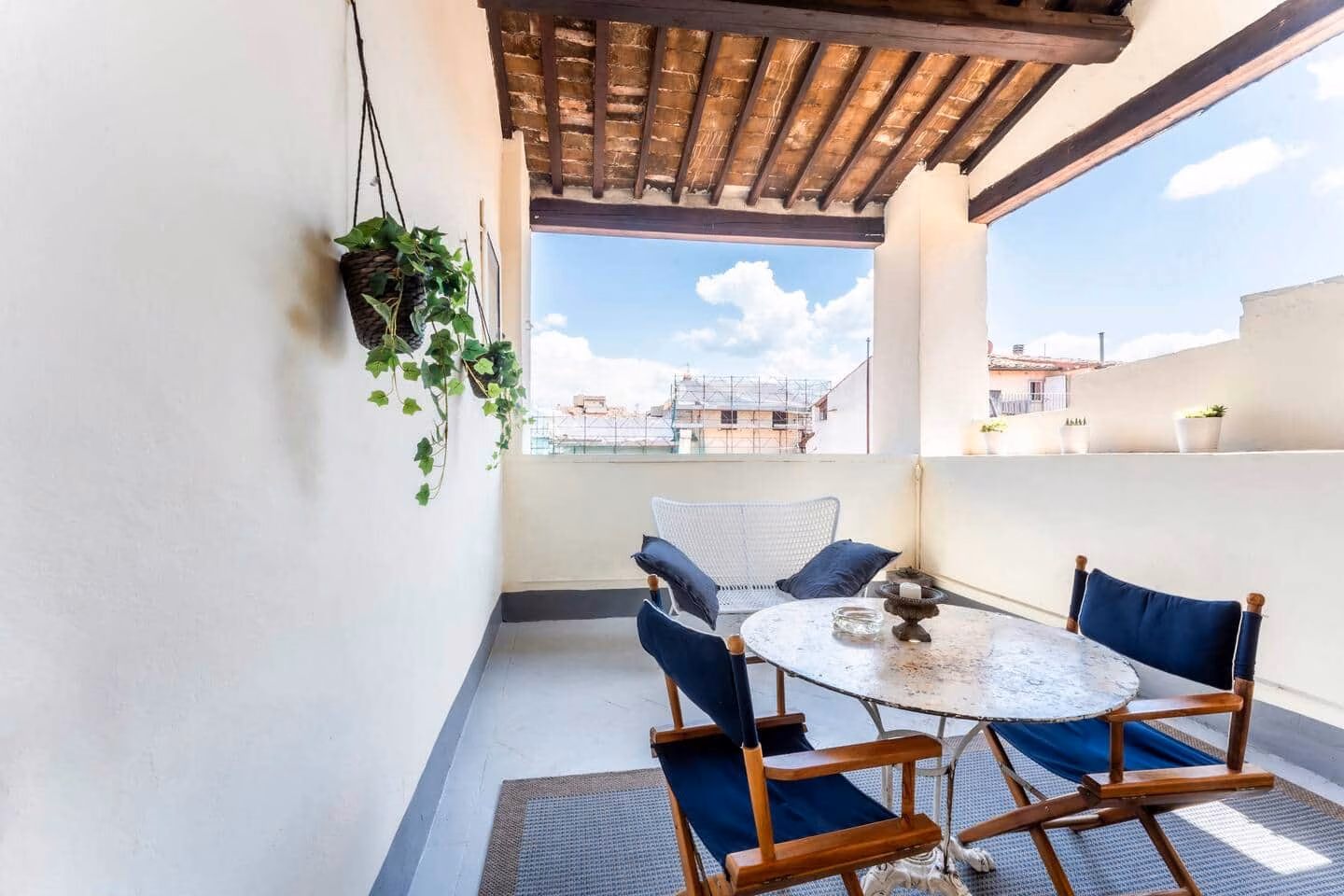 Loggia — covered rooftop loggia with a marble bistro table and navy chairs overlooking the Florence rooftops