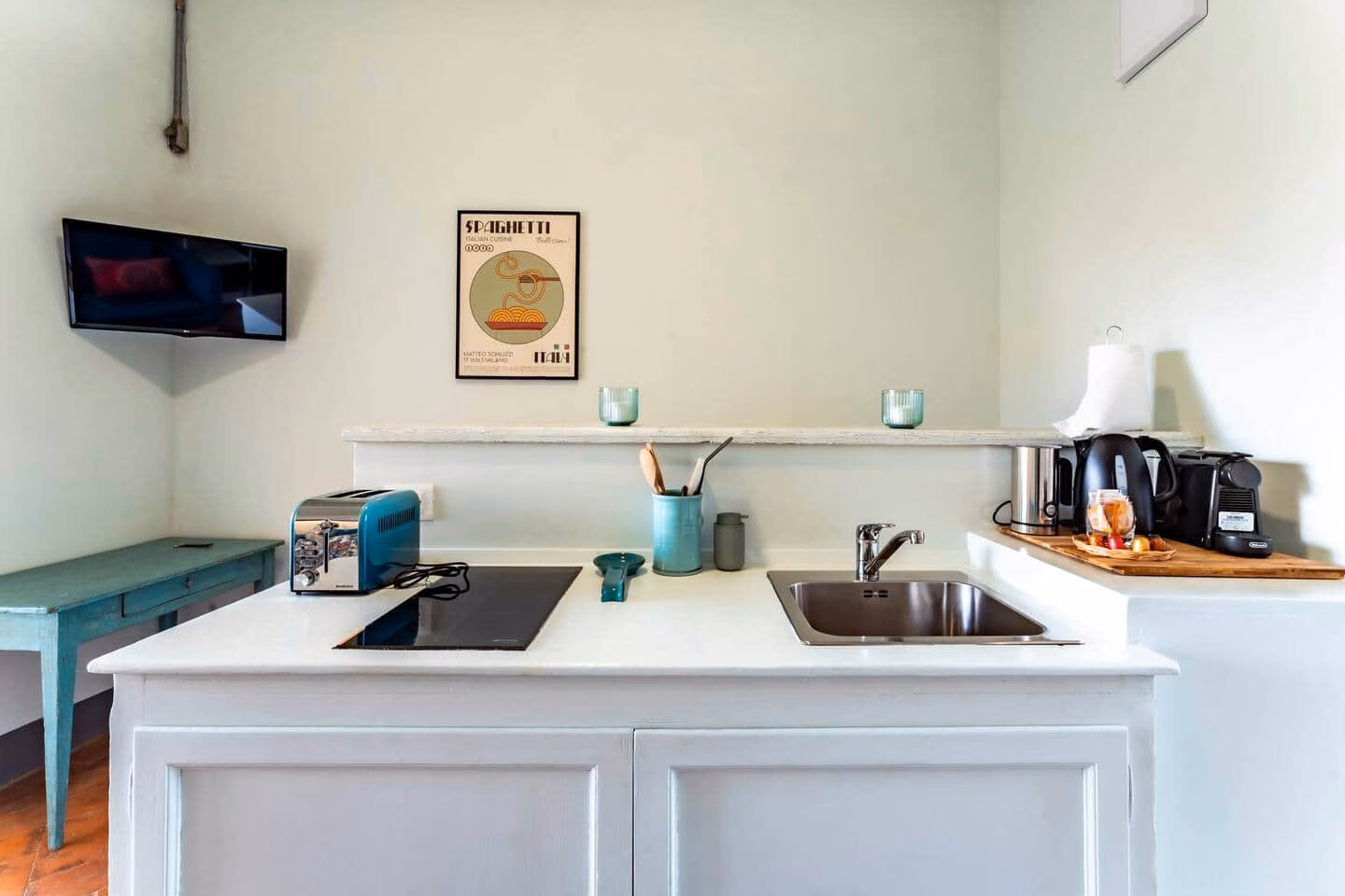 Loggia — kitchenette with pale sage-green walls, a white marble-topped island and an induction hob