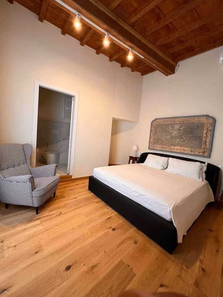 Sprone Right — double bedroom with white linen, a carved antique headboard panel and exposed beams above
