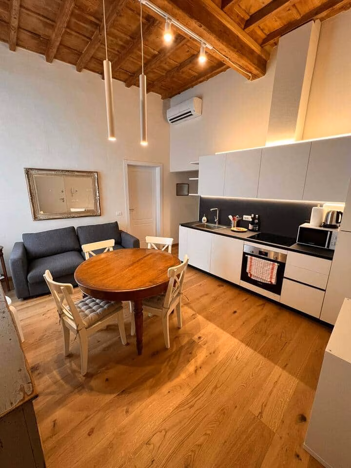 Sprone Right — fitted white kitchen with oven and hob beside a round dining table beneath beamed ceilings